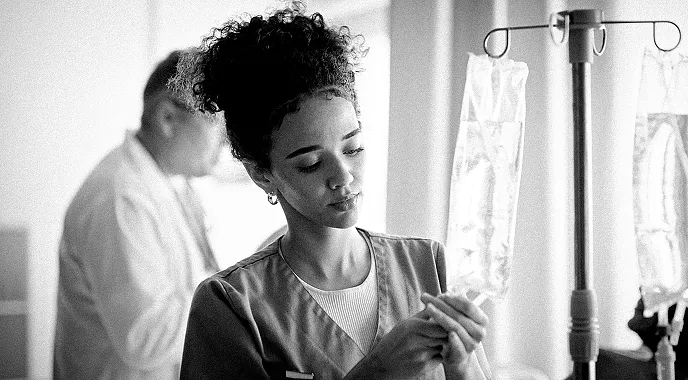 A young healthcare professional prepares an IV bag for a patient.