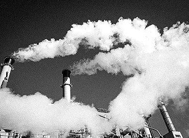 Smoke stacks billowing thick smoke into the sky.