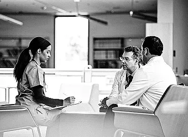 Three healthcare professionals in a hospital facility have a focused conversation.